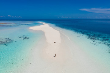 Aerial view of a man walking on the white sand bar in the tropical destination. Hawaii French polynesia Maledives Philippines.