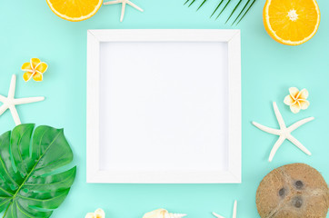 Top view frame with copy space, at blue mint background. Travel mockup concept flat lay with oranges, coconut and starfishes