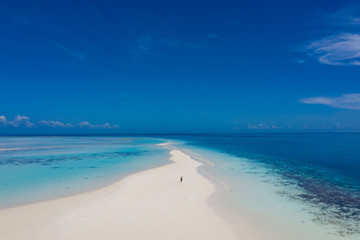 Fototapeta na wymiar Aerial view of a man walking on the white sand bar in the tropical destination. Hawaii French polynesia Maledives Philippines.