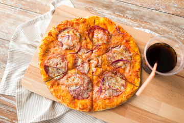 fast food and unhealthy eating concept - close up of sliced homemade pizza with cup of cola drink on wooden table