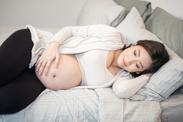 Obraz na płótnie Canvas Beautiful asian pregnant woman is sleeping on bed
