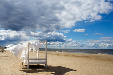 View of the beautiful sunny beach landscape with bed and white curtaince on Baltic sea, blue sky clouds