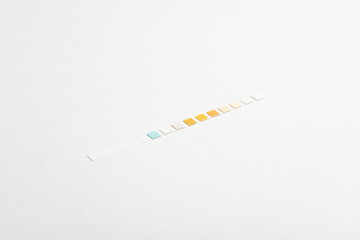 Obraz premium A single unused urine reagent strip for medical testing set on a plain white background.