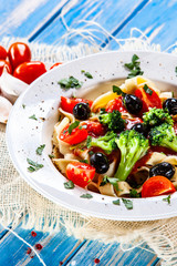 Pasta with herbs and vegetables on wooden background