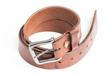 A used men's thick leather brown belt with patina from use deliberately and artistically set on a...