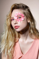 Model with amazing blue eyes and wavy hair having petals around eye