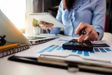 Business women calculates financials with graph paper on the table on the cost of home office.