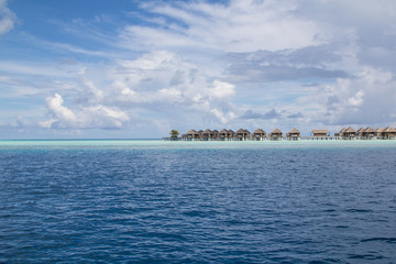 Fototapeta na wymiar Seaside wooden bungalows on a shallow reef in a luxury resort in the atoll of the Maldives threatened by climate change