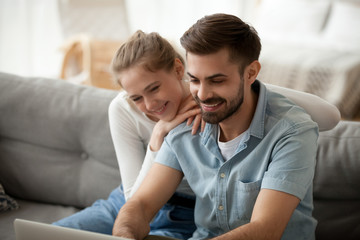 Fototapeta na wymiar Happy couple spending time together at home, using laptop