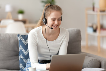 Smiling woman wearing headset, using laptop, looking at screen