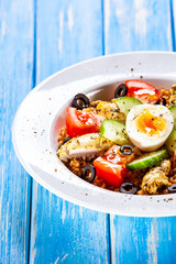 Grilled chicken meat with groats and boiled egg on wooden table