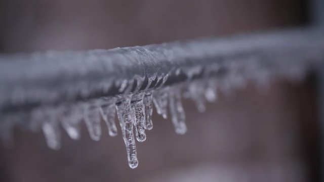 Frozen stalactites hanging from a metal rail with focus pull.