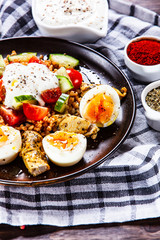 Grilled chicken meat with groats and boiled egg on wooden table