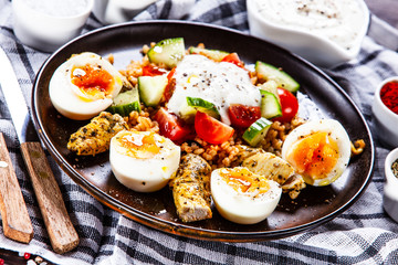 Grilled chicken meat with groats and boiled egg on wooden table