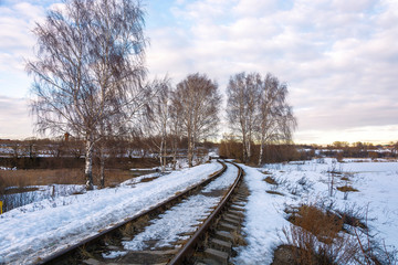 Beautiful March landscape with birches and a railroad leaving into the distance.
