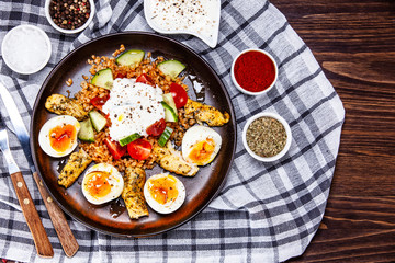 Grilled chicken meat with groats and boiled egg on wooden table