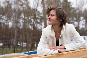 The girl in a white jacket with a thoughtful look on the street.