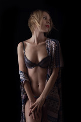 Middle-aged woman in bra on a dark background.