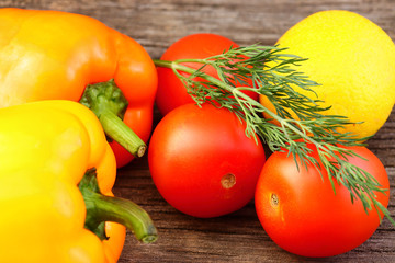 Bright vegetables and fruits (yellow and orange peppers, red tomatoes, yellow lemon, green dill).