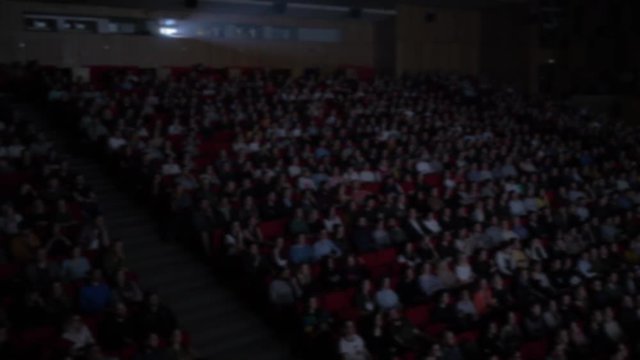 People watch movies in the cinema. General plan of the full cinema in the cinema. The frame is out of focus. Background