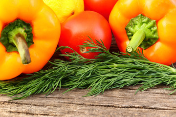 Bright vegetables and fruits (yellow and orange peppers, red tomatoes, yellow lemon, green dill).