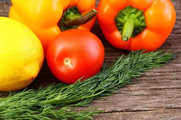 Bright vegetables and fruits (yellow and orange peppers, red tomatoes, yellow lemon, green dill).
