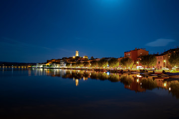 Fototapeta na wymiar Panorama notturno di Marta VT, Italia che si riflette sulle acque del Lago di Bolsena.
