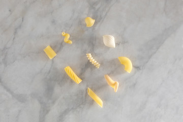 nine types of different pasta rest on a marble table with copy space for your text