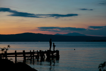 Fototapeta premium Pesca rilassante su un pontile sul lago calmo al tramonto