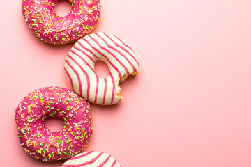 Creative layout made of pink glazed donuts. Flat lay. Food concept. Macro concept. Various decorated doughnuts on soft pink background. Sweet and colourful doughnuts 