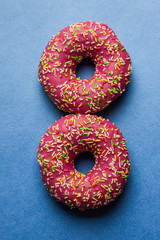 Creative layout made of pink glazed donuts. Flat lay. Food concept. Macro concept. Various decorated doughnuts on blue background. Sweet and colourful doughnuts 