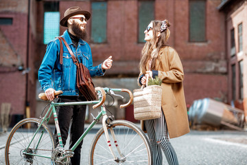 Stylish young man and woman having a conversation standing together with retro bicycle outdoors on the industrial urban background