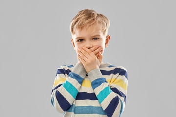 childhood, expressions and people concept - shocked little boy in striped pullover closing his...