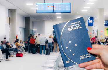 Woman holding a Brazilian passport ready to queue to board airplane