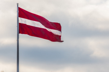 Fototapeta na wymiar Large Latvian flag isolated with clouds in the background