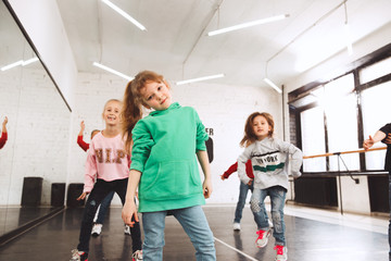 Obraz premium The kids at dance school. Ballet, hiphop, street, funky and modern dancers over studio background. Children showing aerobic element. Teens in hip hop style. Sport, fitness and lifestyle concept.