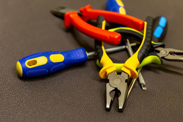 building design close-up of a bunch of yellow open black chrome cutters screwdrivers on a brown background