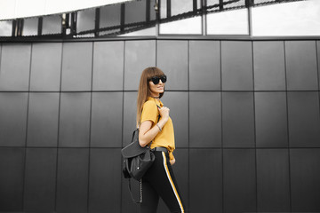 Beautiful brown-haired model girl in the yellow sleeveless shirt and in the fashionable sunglasses...