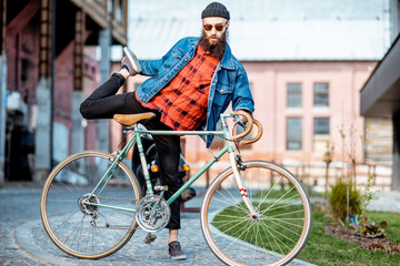 Portrait of a bearded man as a crazy hipster having fun with retro bicycle outdoors on the...