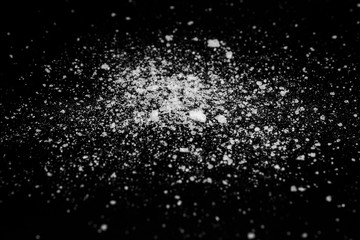 white crystalline powder on a black background. sugar dust 