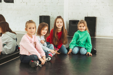 The kids sitting at dance school. Ballet, hiphop, street, funky and modern dancers concept. Studio background. Teens in hip hop style. Sport, fitness and lifestyle concept.