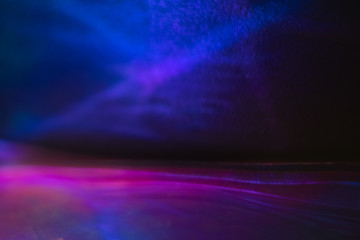 Blurred neon blue and purple abstract lines on dark background. Defocused lens flare glow effect.