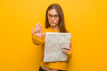 Young pretty caucasian woman putting hand in front. She is holding a map.