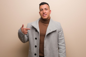 Young latin business man person pointing by hand to a shirt copy space, proud and confident