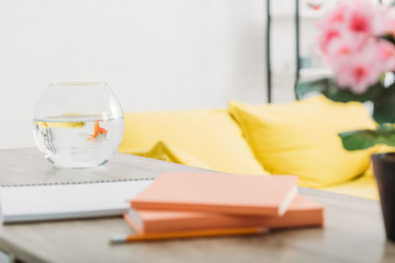 selective focus of aquarium with gold fish on wooden table near books