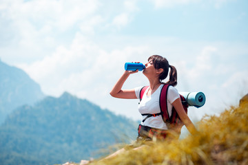 Young female hiker sitting and drinking water,enjoying nature