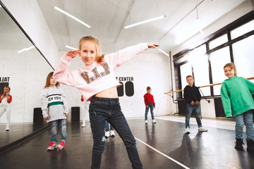 The kids at dance school. Ballet, hiphop, street, funky and modern dancers over studio background. Children showing aerobic element. Teens in hip hop style. Sport, fitness and lifestyle concept.