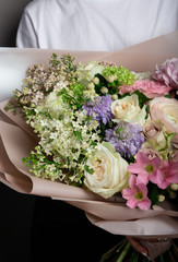 beautiful delicate bouquet in hand, a bouquet of fresh flowers, handmade, work of a florist, on a gray wall