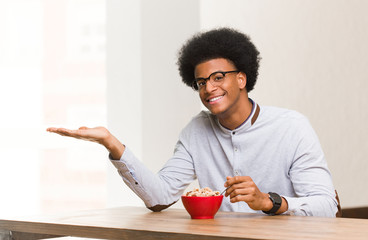 Fototapeta na wymiar Young black man having a breakfast holding something with hand