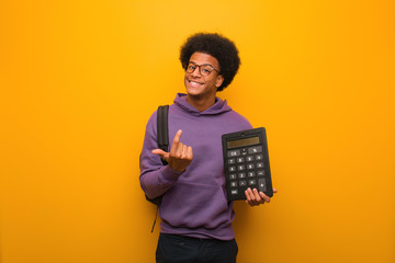 Young african american student man holding a calculator inviting to come